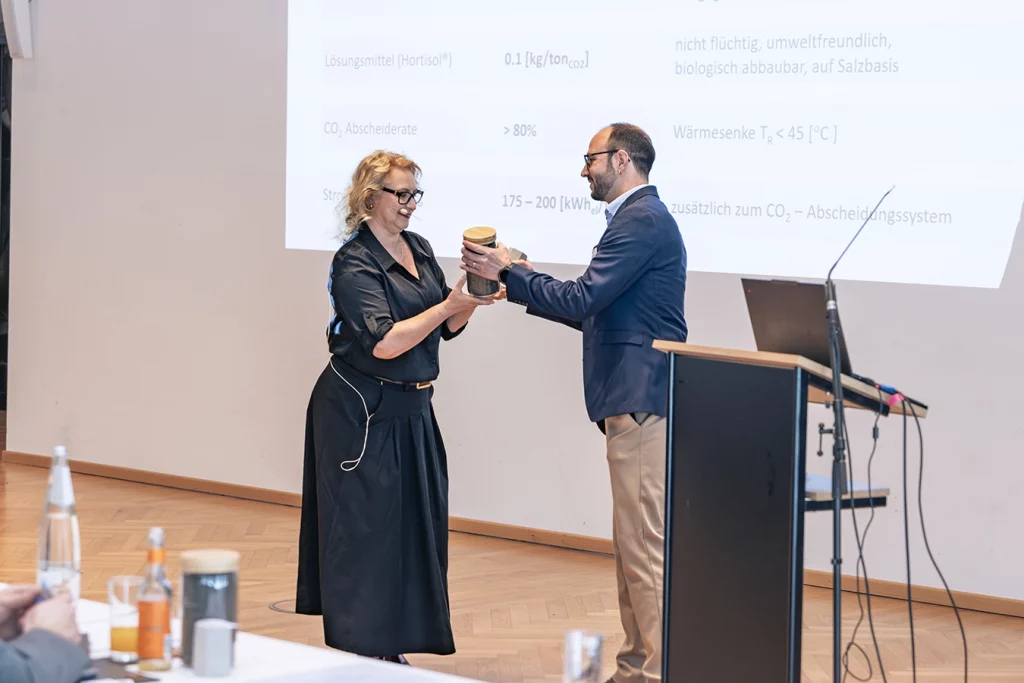Yvonne Bosch übergibt ein Geschenk an einen Referenten auf dem Holzaschekongress 2026